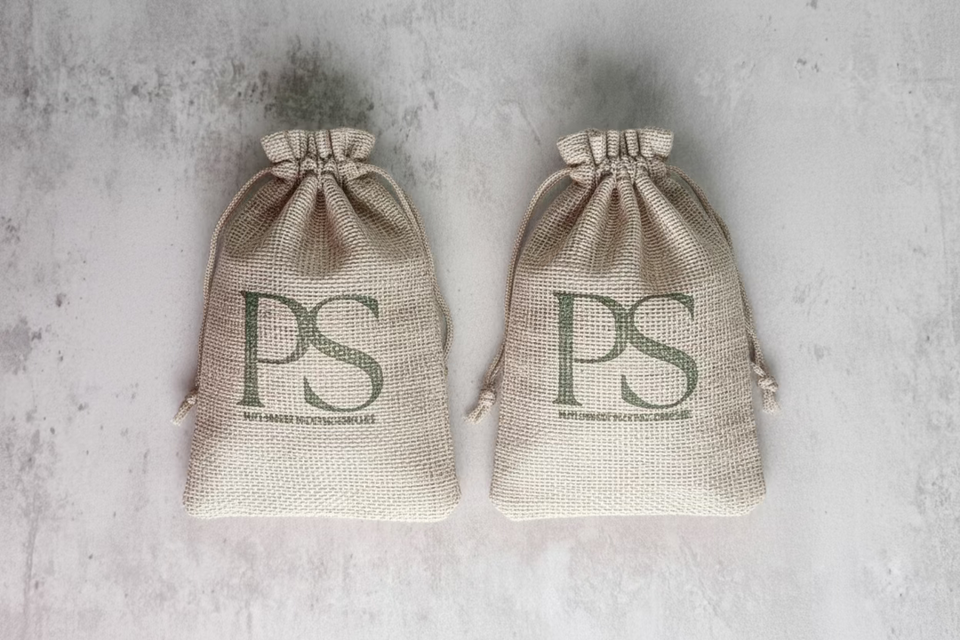 Two burlap sacks with 'PS' monogram, displayed on a stone surface, likely containing the soap sacks for shoe freshening.